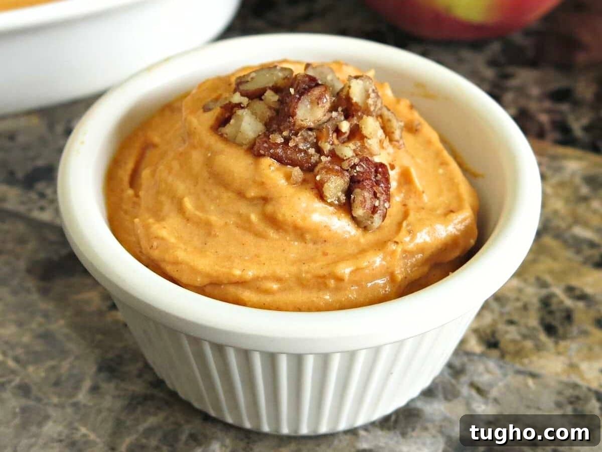 15 Make-Ahead Thanksgiving Recipes to Prep Now 13 White ramekin with pumpkin cream cheese dip topped with candied pecans.