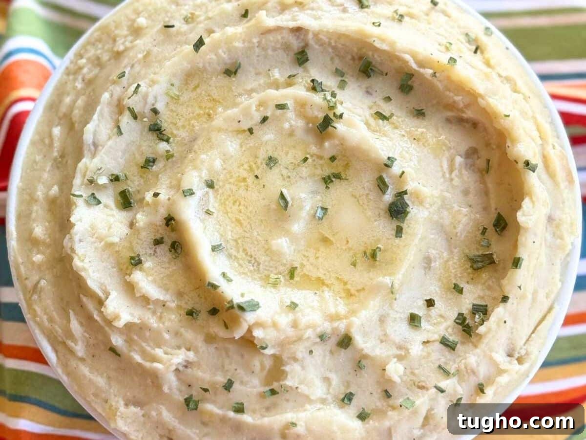 15 Make-Ahead Thanksgiving Recipes to Prep Now 3 White bowl with crockpot mashed potatoes with butter pooling in the center.