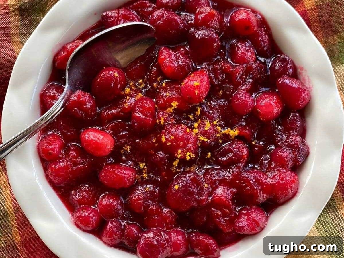 15 Make-Ahead Thanksgiving Recipes to Prep Now 5 Whole cranberry sauce in a fluted bowl with zested orange and a spoon.
