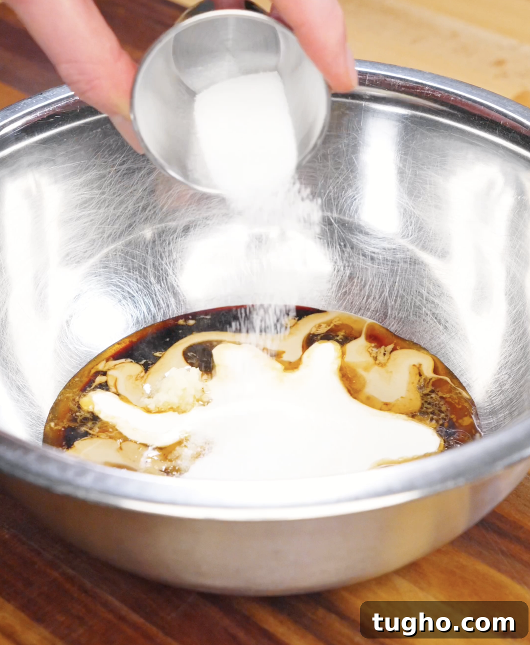 Creamy Sesame Noodles with Garlic Soy Sauce 6 Sugar being poured into a bowl with sesame paste, soy sauce, garlic, and cream to make creamy sesame noodle sauce.