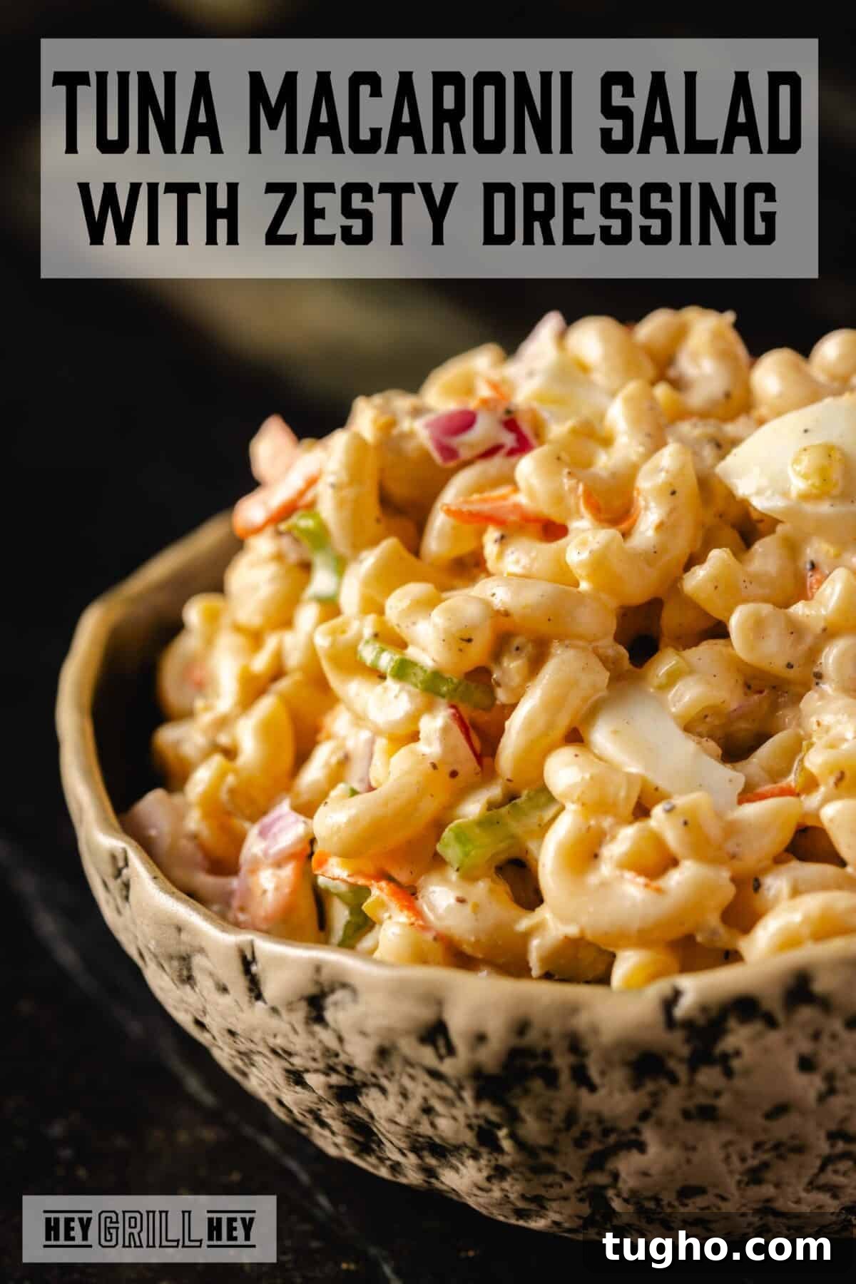 Tuna Macaroni Salad with Zesty Homemade Dressing Recipe 2 A bowl of tuna macaroni salad with chopped eggs and veggies. The text overlay reads "Tuna Macaroni Salad" at the top, and "Hey Grill Hey" at the bottom.