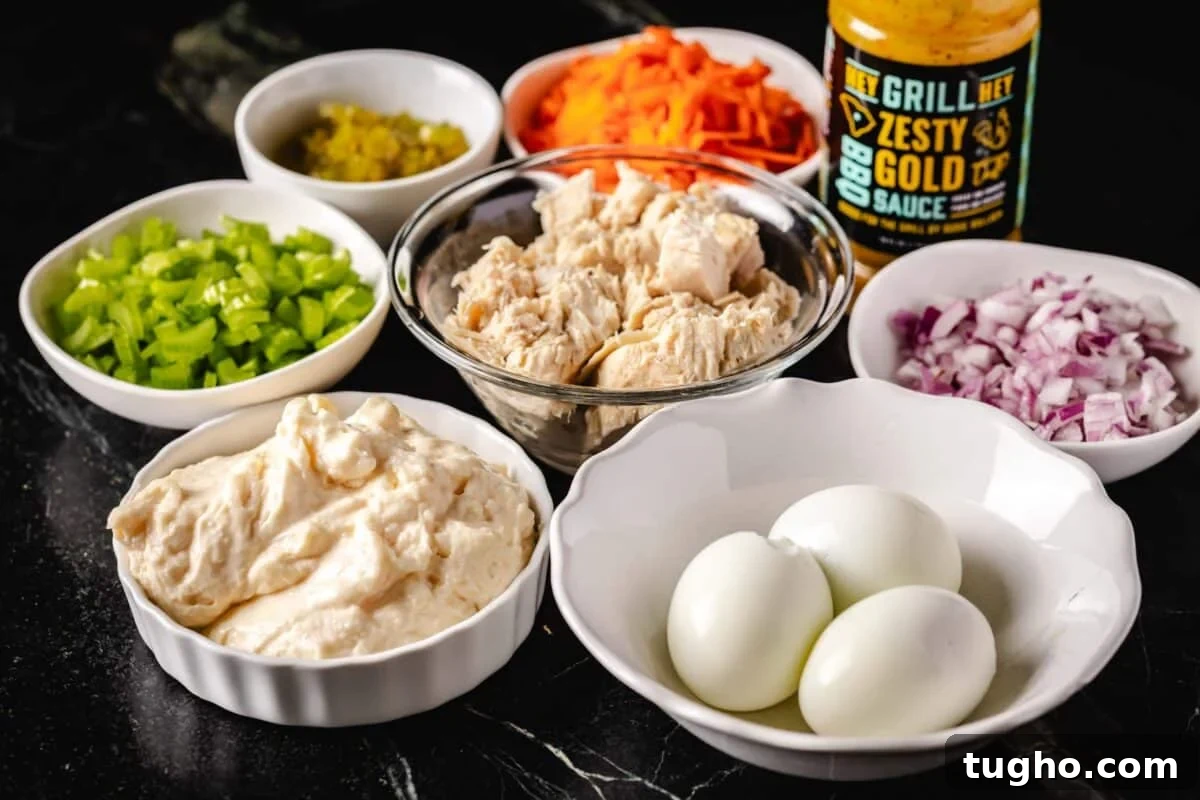 Tuna Macaroni Salad with Zesty Homemade Dressing Recipe 3 A metal bowl filled with tuna, surrounded by white glass bowls with eggs, and chopped veggies.
