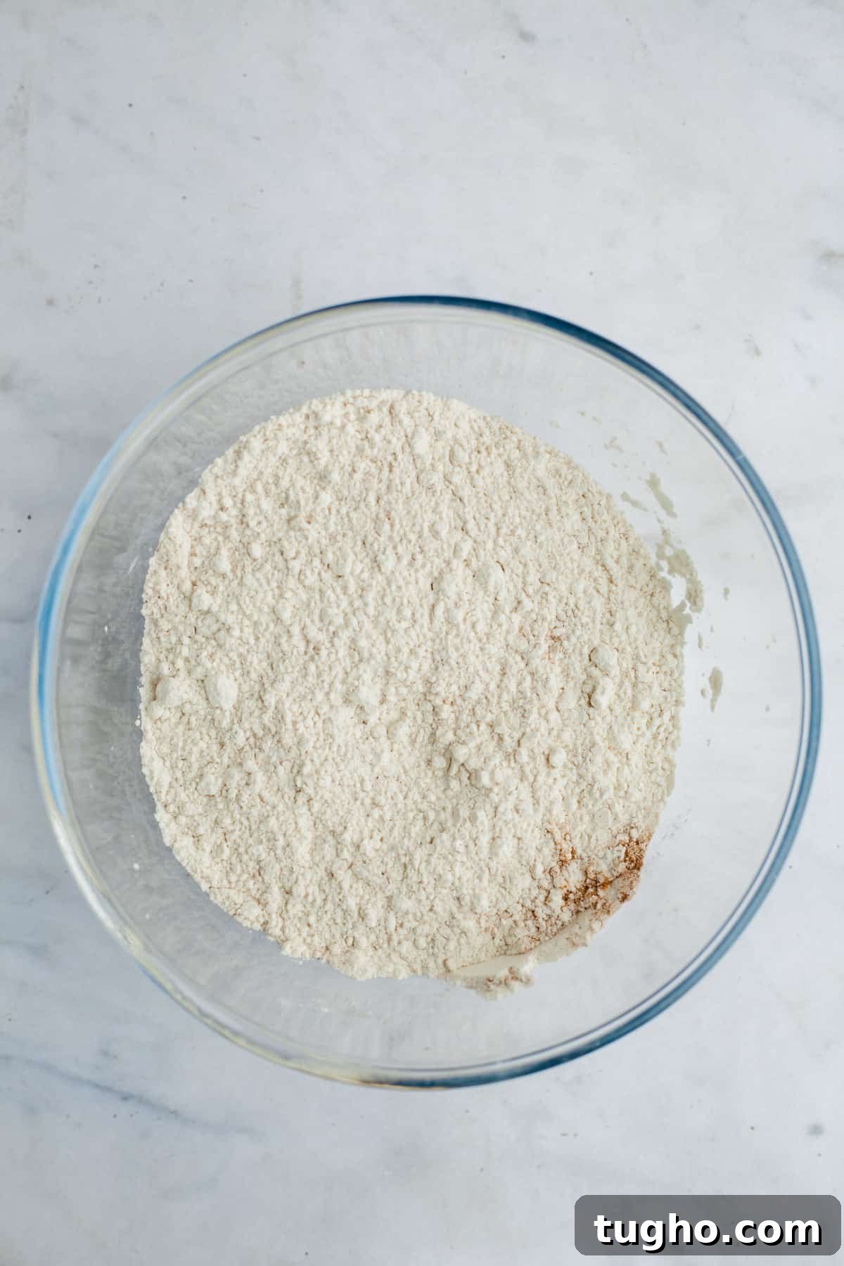 A large glass bowl with flour and spices in it