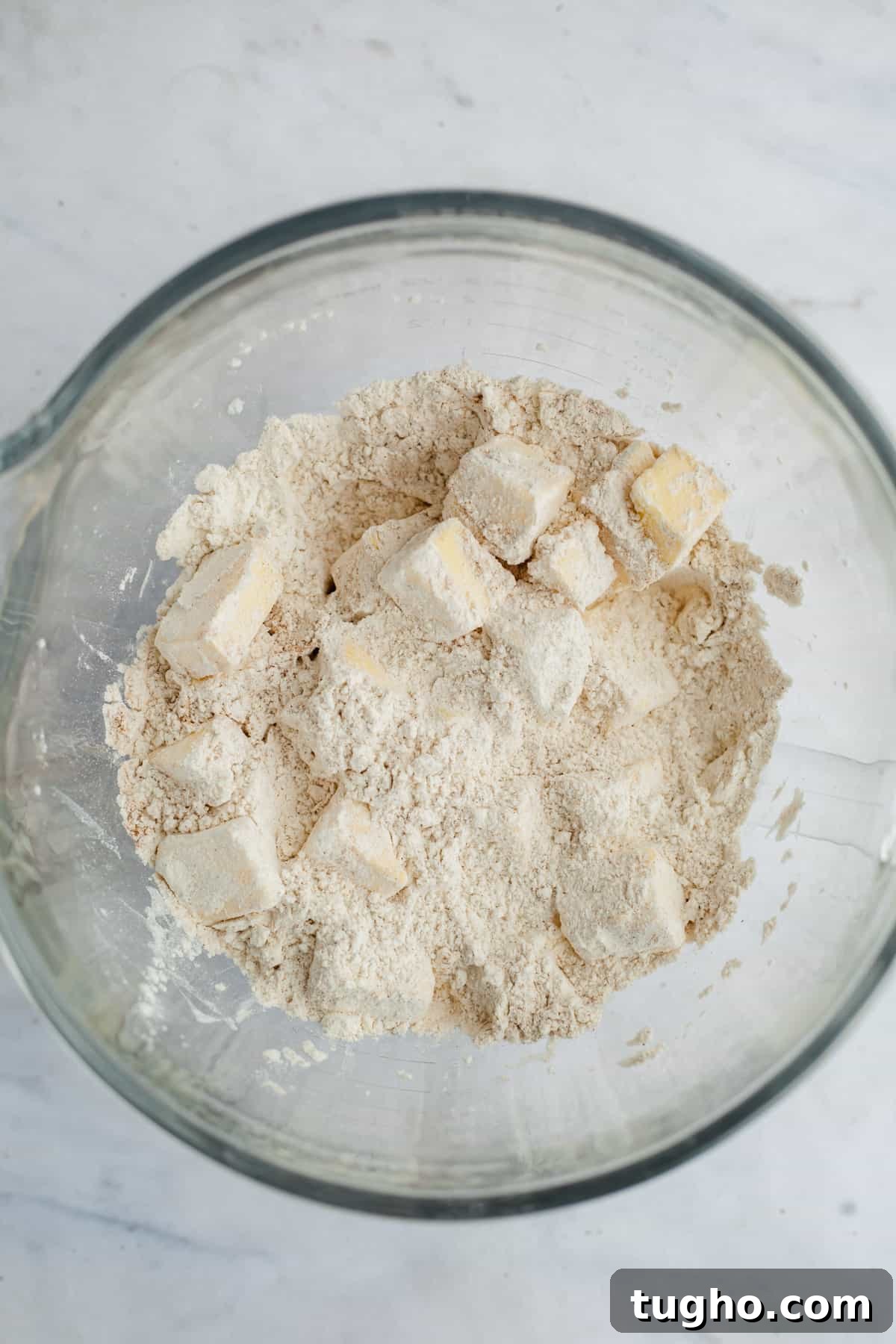 cubes of butter tossed in flour in a large glass bowl