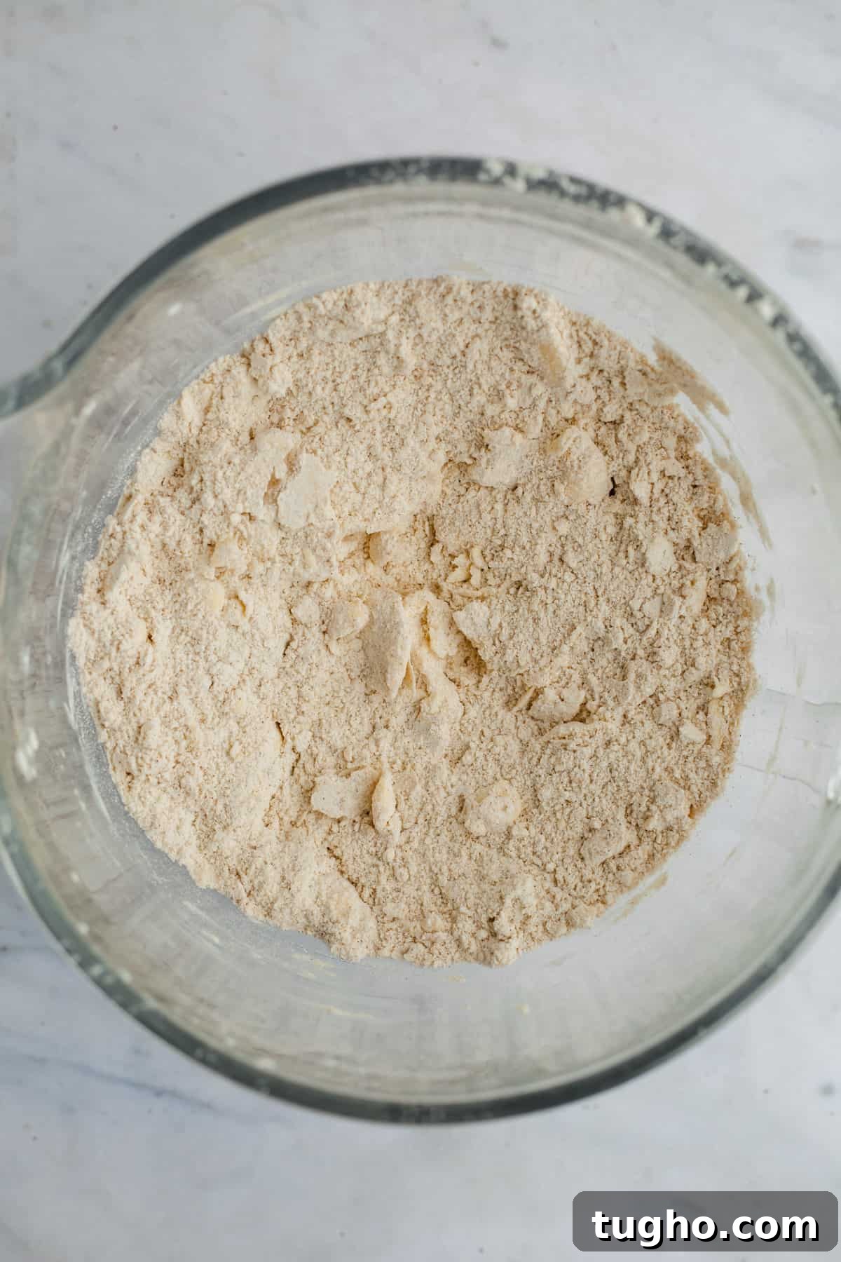 A large glass bowl with flour and pieces of butter