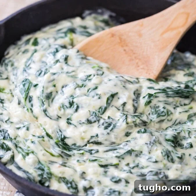 wooden spoon stirring thick and creamy creamed spinach