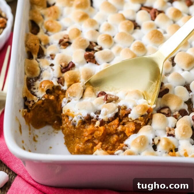 Gold spoon scooping sweet potato casserole out of a white dish.