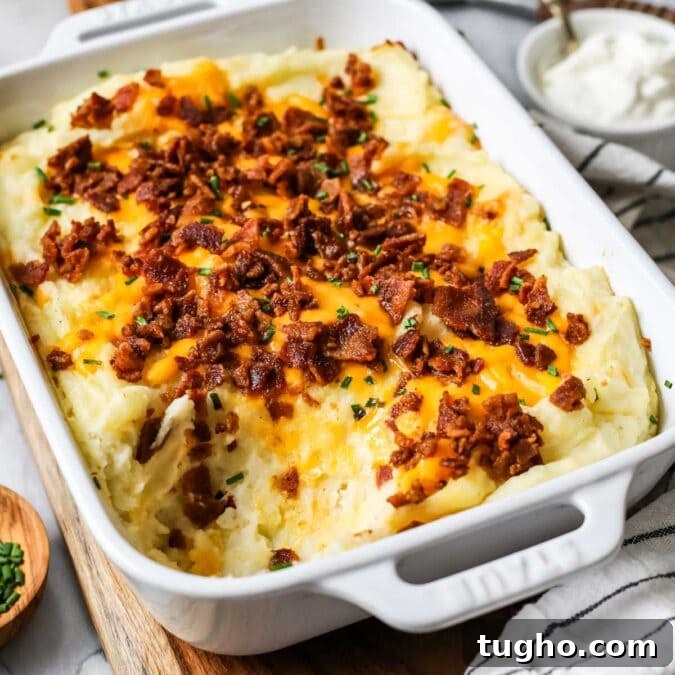 Dish of loaded mashed potato casserole with one serving missing.