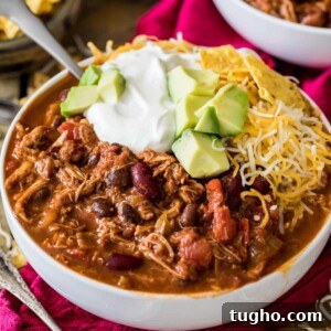 Bowl of turkey chili topped with sour cream, avocado, and shredded cheese.