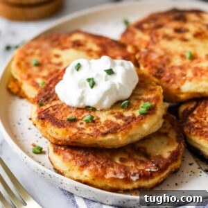 Plate of mashed potato pancakes topped with sour cream and chives.