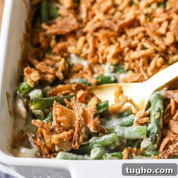 Serving spoon scooping green bean casserole out of a dish.