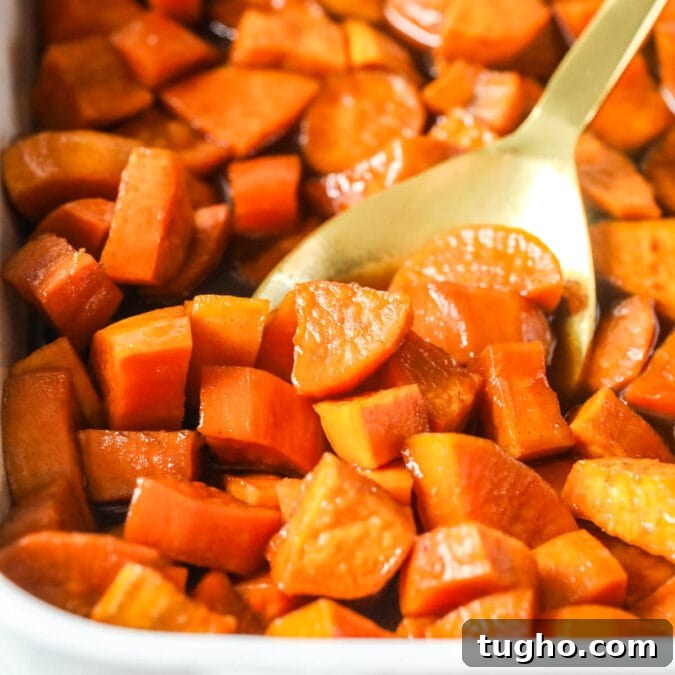 Casserole dish of candied yams with a gold spoon scooping a serving.