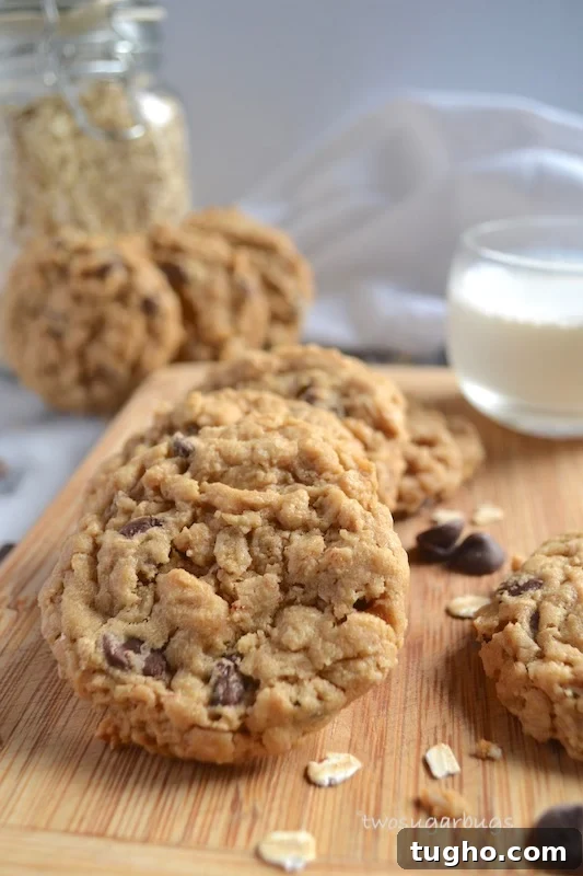 Chewy Oatmeal Peanut Butter Chocolate Chip Cookies Recipe 2 cookies on a cutting board with a cup of milk in the background