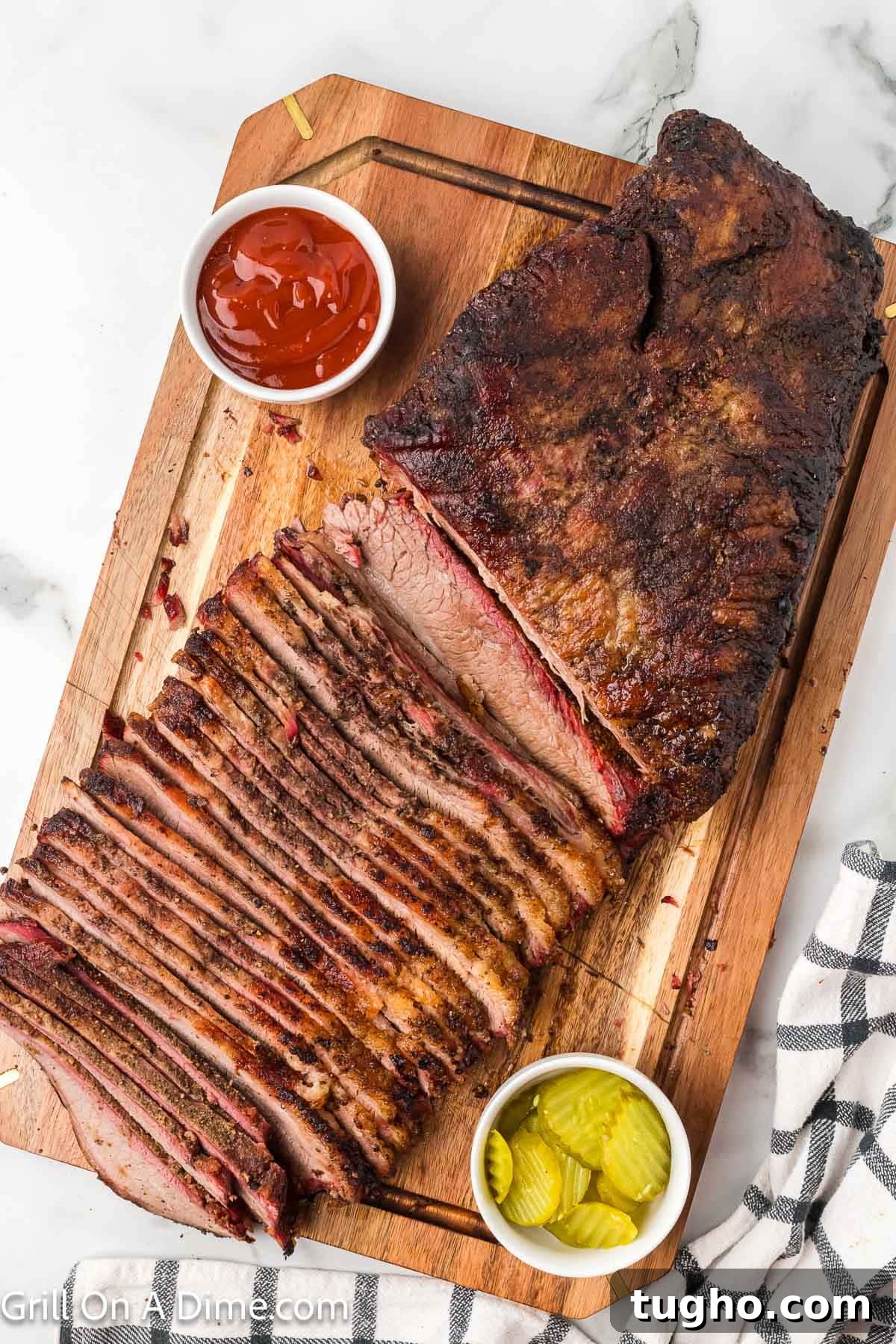 Authentic Texas Style Brisket Recipe 12 Sliced brisket on a cutting board with small bowls of sliced pickles and ketchup