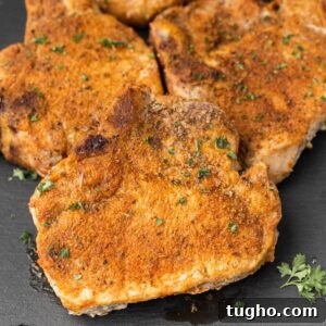 Pork chops on a black slate with parsley.