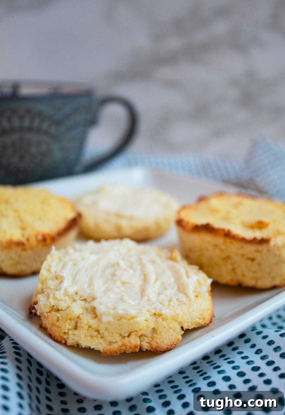 Keto Cornbread Muffins - Low-Carb, Fluffy & Savory 2 keto cornbread on a white plate cut in half in front of a cup of coffee