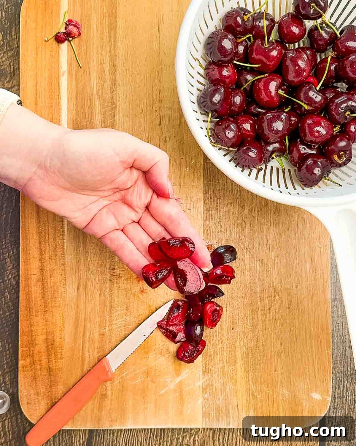 Homemade Cherry and Peach Cobbler Recipe 5 A hand holding a cherry cut into quarters.