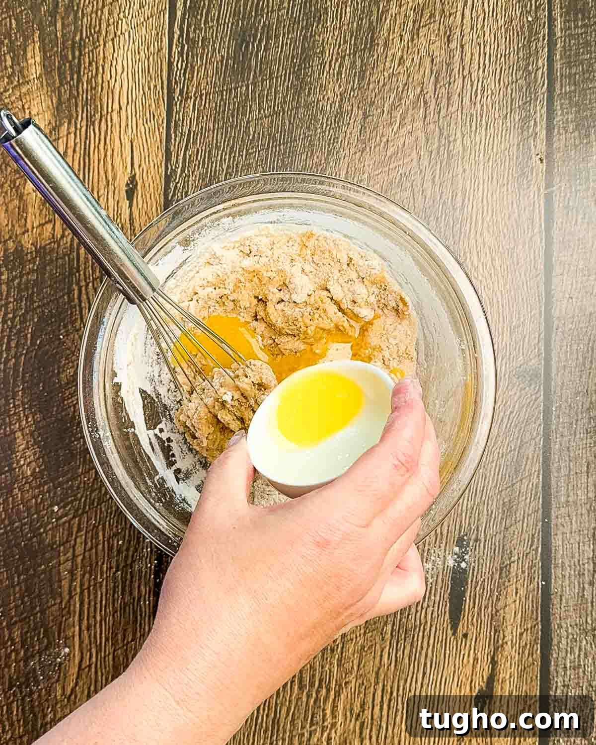 Homemade Cherry and Peach Cobbler Recipe 8 A hand adding the melted butter to a mixing bowl with the cobbler topping ingredients.