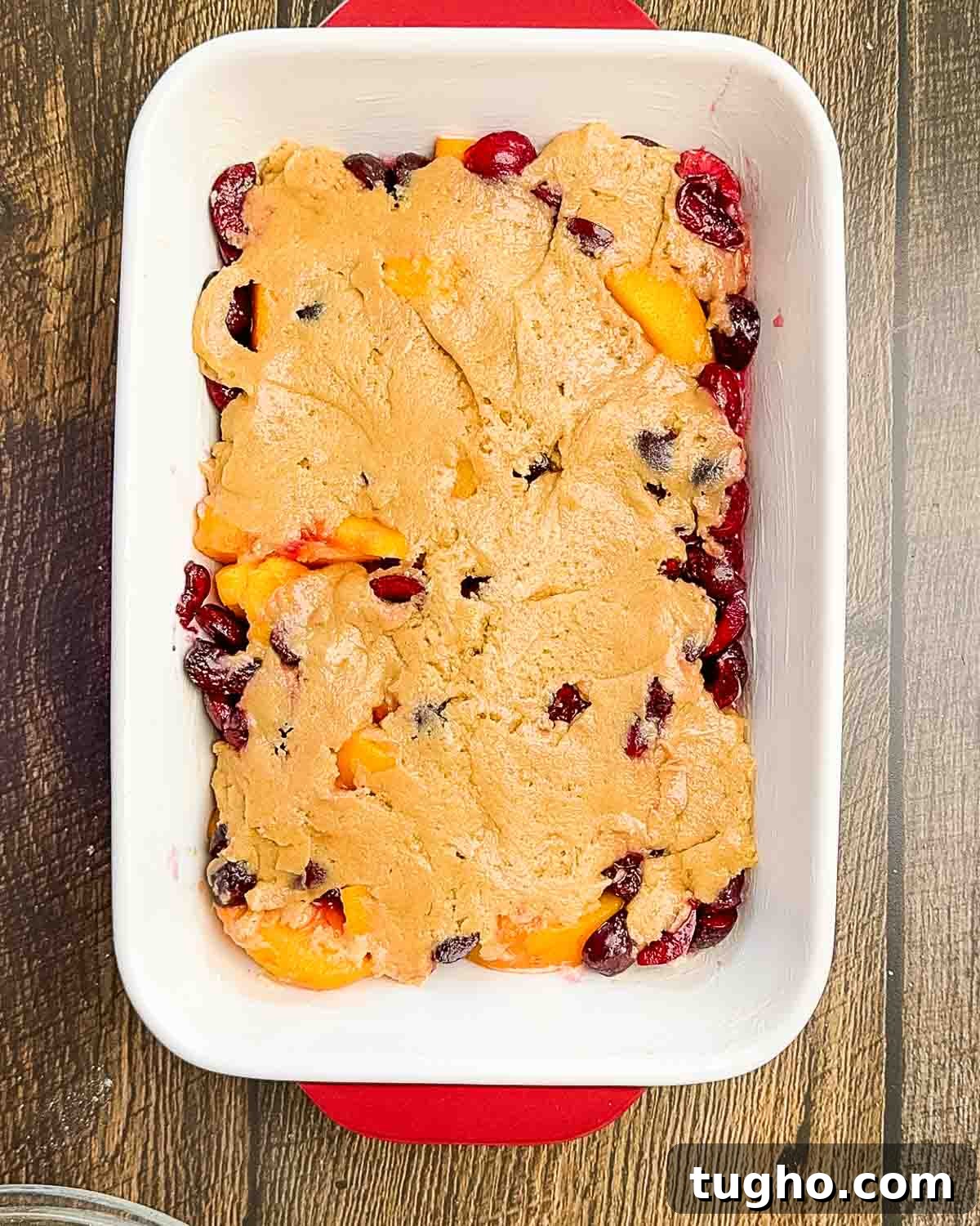 Homemade Cherry and Peach Cobbler Recipe 9 The prepared topping spread on top of the fruit mixture in a baking dish.