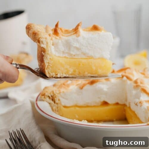 a slice of lemon meringue pie being lifted out with a serving knife.