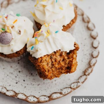 Moist Carrot Cupcakes with Cream Cheese Frosting 14 A small plate with three carrot cupcakes, one has a bite taken out of it.
