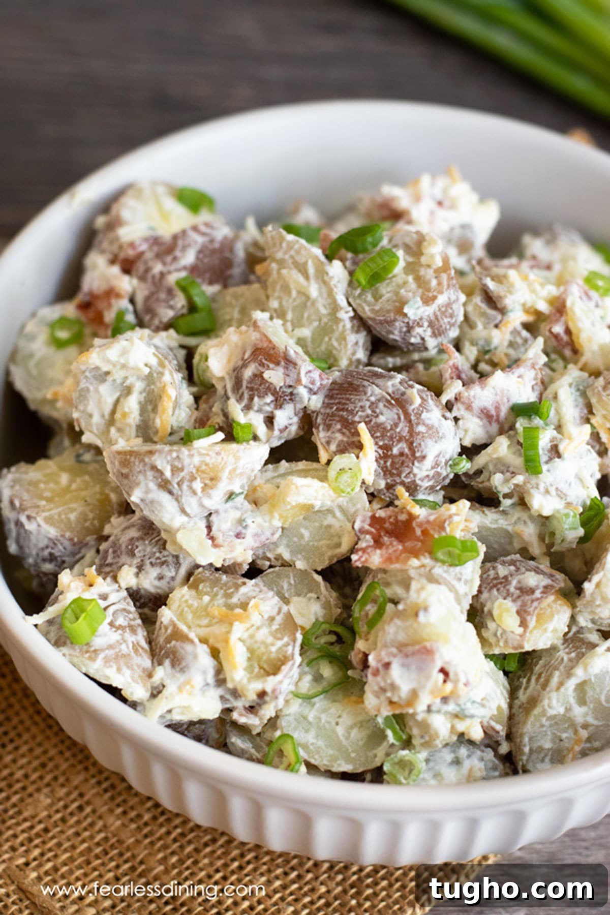12 Sides That Pair Perfectly with Sloppy Joes 11 A white bowl filled with loaded baked potato salad.