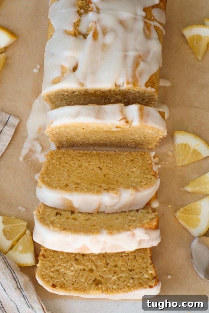Moist Gluten-Free Lemon Loaf Recipe 2 Gluten free lemon loaf with lemon glaze on parchment paper with slices of lemon