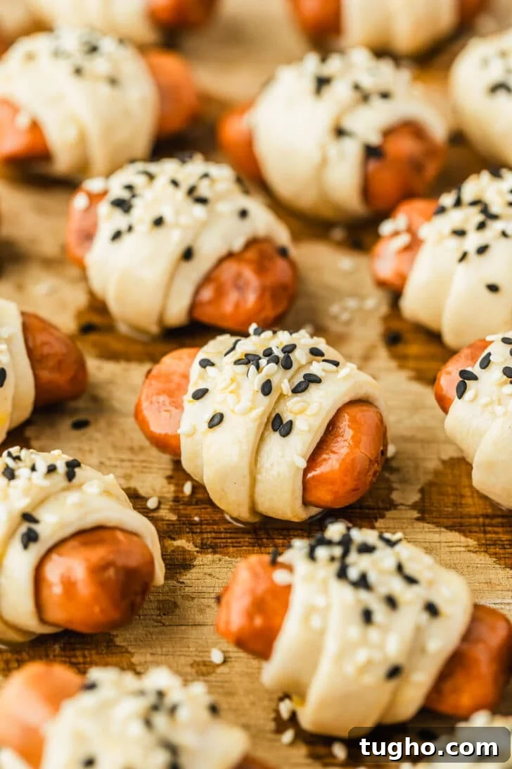 3-Ingredient Air Fryer Pigs in a Blanket Recipe 7 Raw air fryer pigs in a blanket with sesame seeds on a wood board.