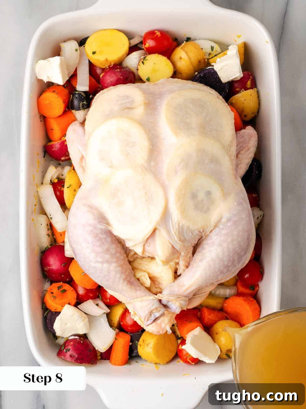 Crispy Oven Roasted Lemon Chicken with Garlic and Herbs 8 trussed chicken on vegetables in white roasting dish.