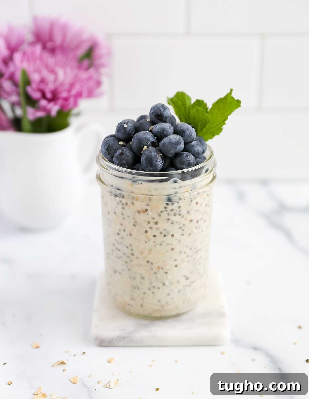 A jar of oatmeal topped with blueberries and mint
