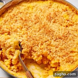 Large gray pot filled with cooked butternut squash pasta with spoon scooping out a serving of pasta.