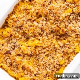 White baking dish filled with baked Sungold pasta with breadcrumbs all over the top sitting on white marble surface.