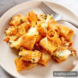 White plate filled with serving of lasagna casserole with fork resting on plate as well.