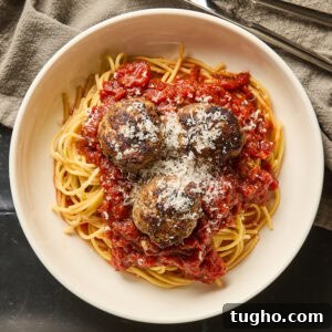 A serving of spaghetti with meatballs on a small plate.