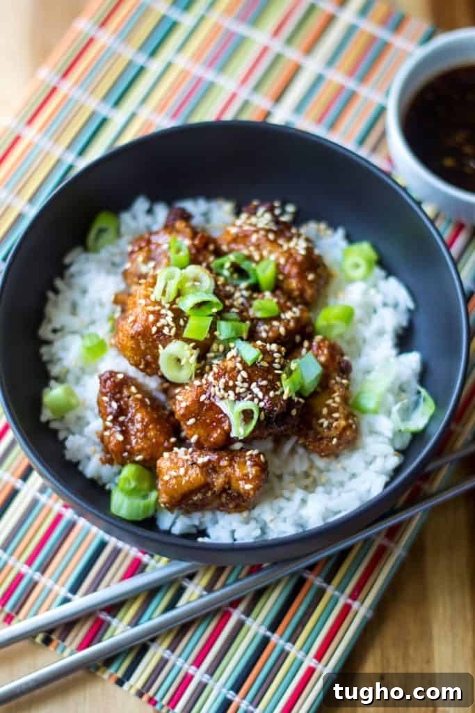 Sticky sweet and spicy chicken rice bowl with baked chicken bites in a glossy sauce