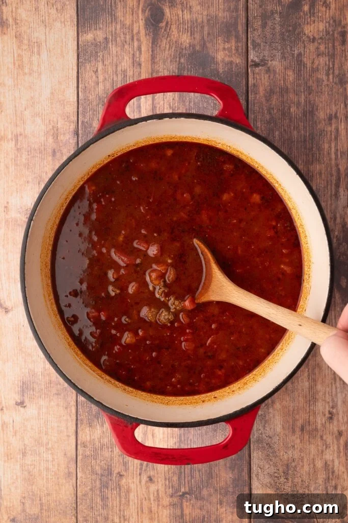 adding tomatoes and liquid to dutch oven for Texas Chili