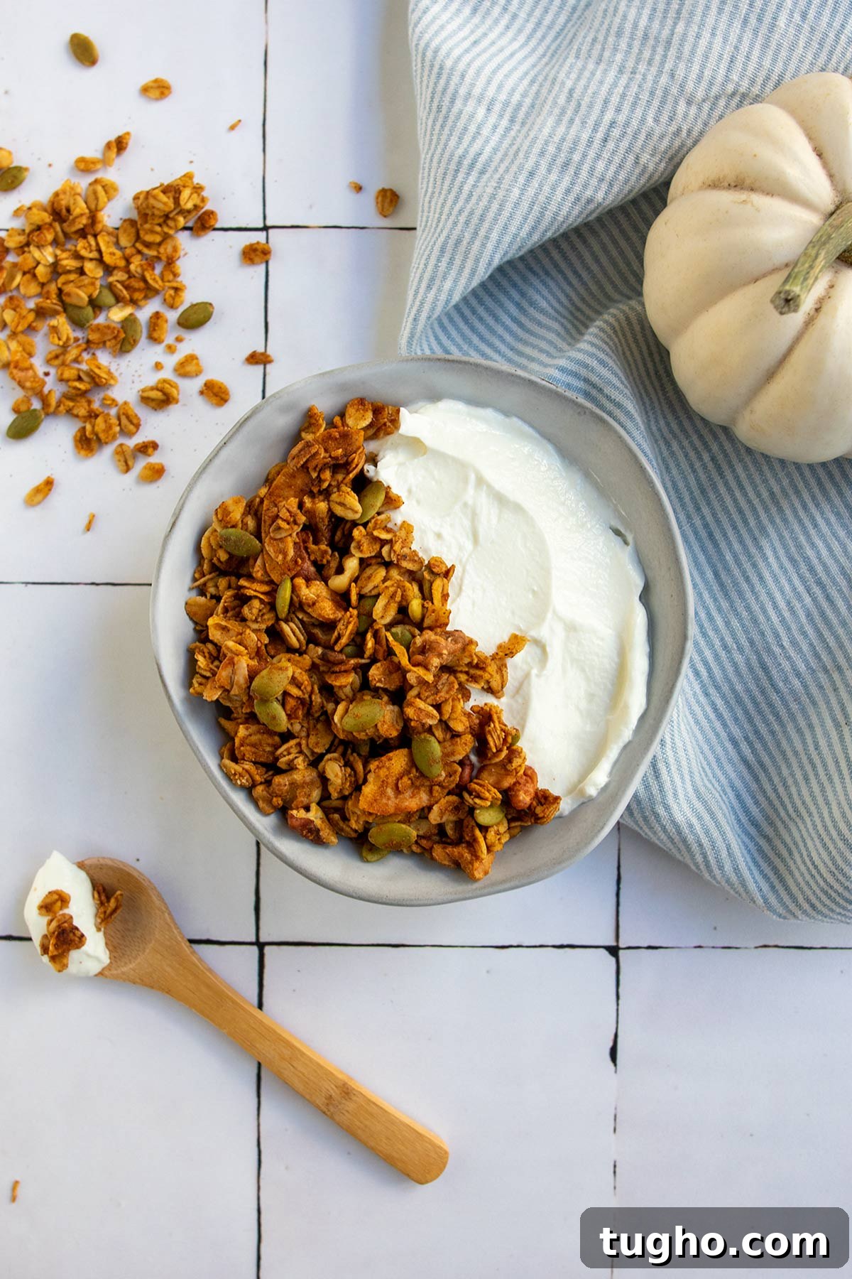 Pumpkin Granola Recipe with Maple or Date Syrup 2 Grey bowl with yogurt and granola, wooden spoon and striped linen napkin and white pumpkin.