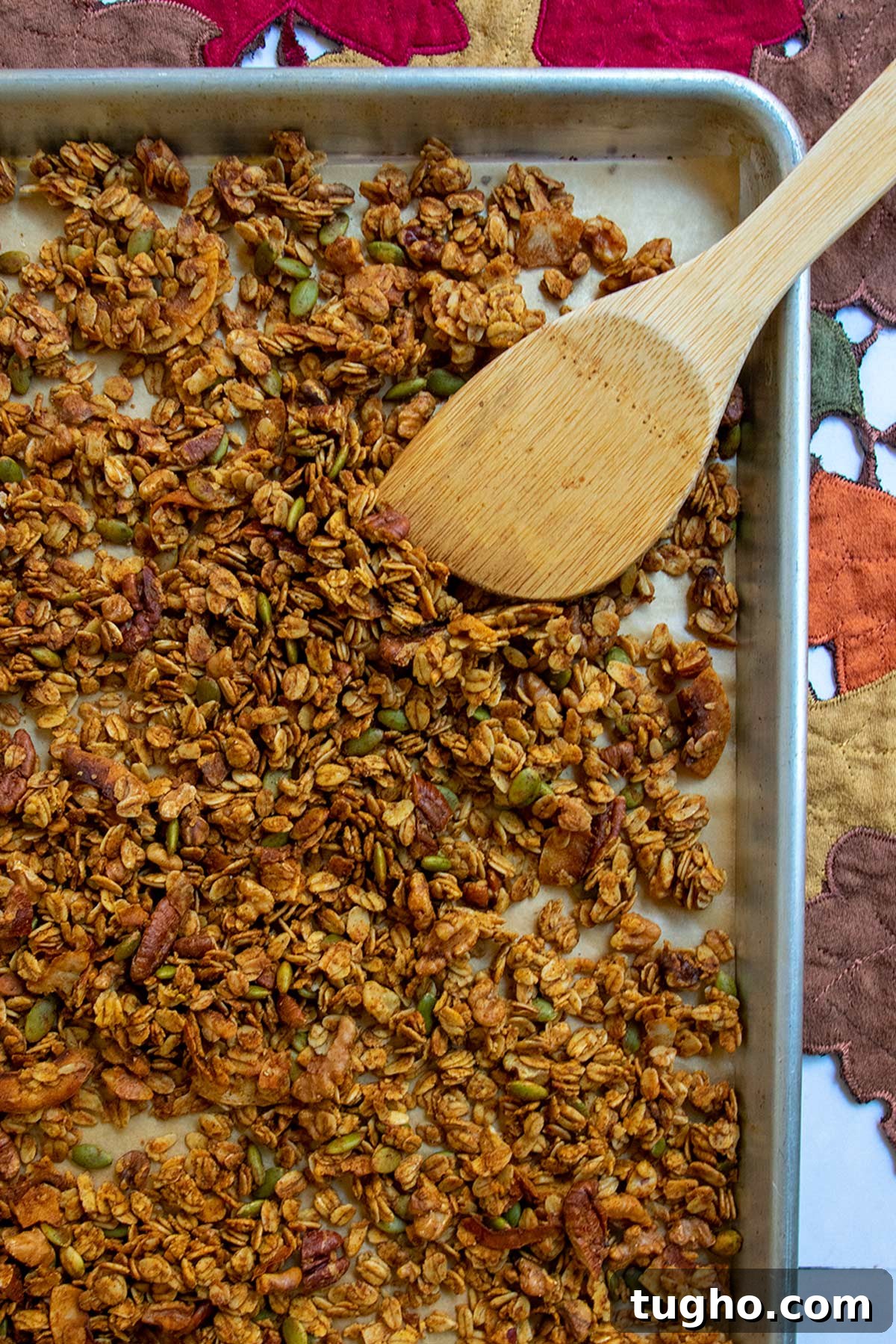 Pumpkin Granola Recipe with Maple or Date Syrup 8 Baked granola on sheet tray with wooden mixing paddle.