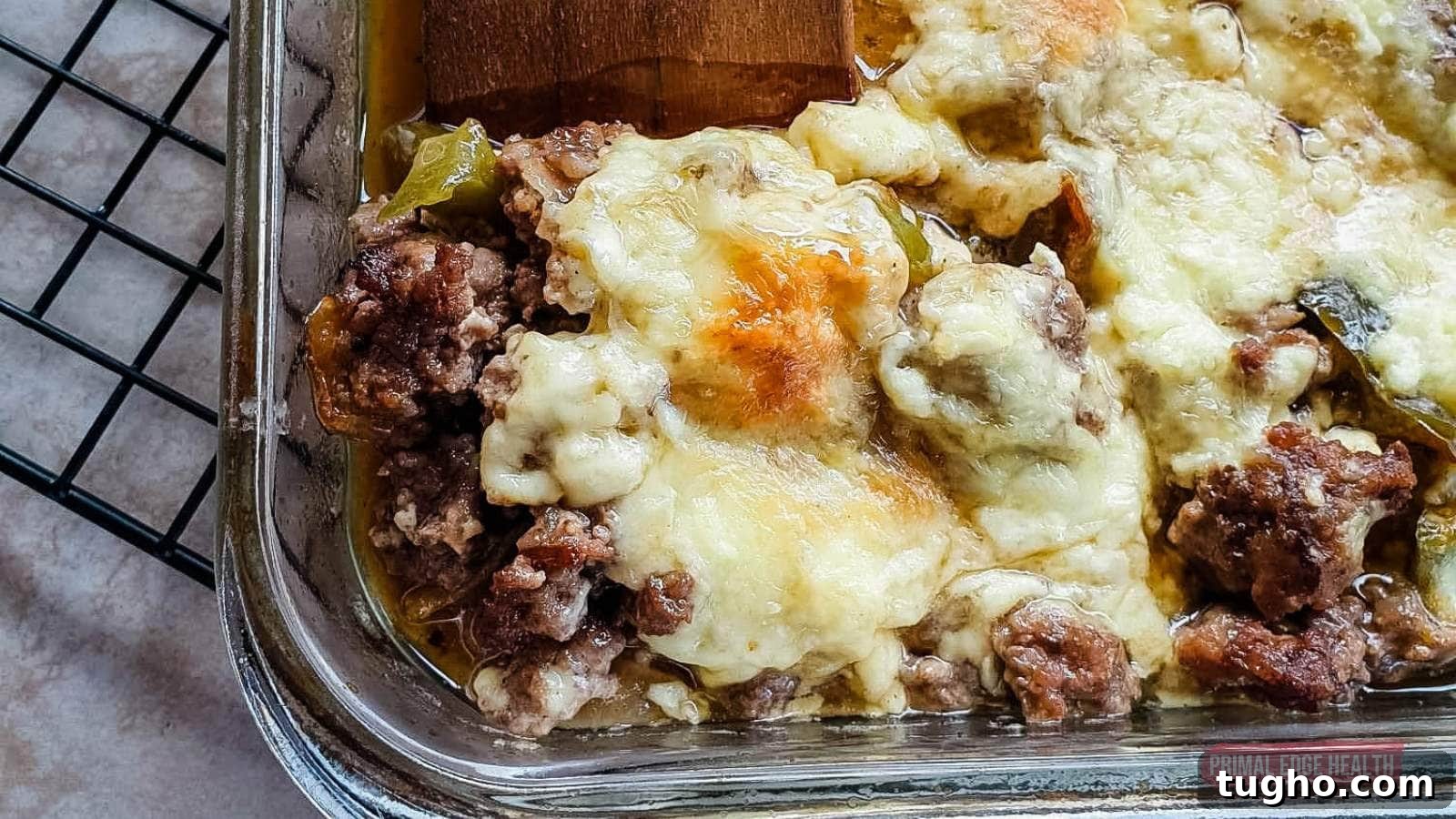 17 No-Fuss Dinners That Make the Whole Family Smile 12 Image shows a wooden spatula cutting philly cheesesteak casserole from baking dish.