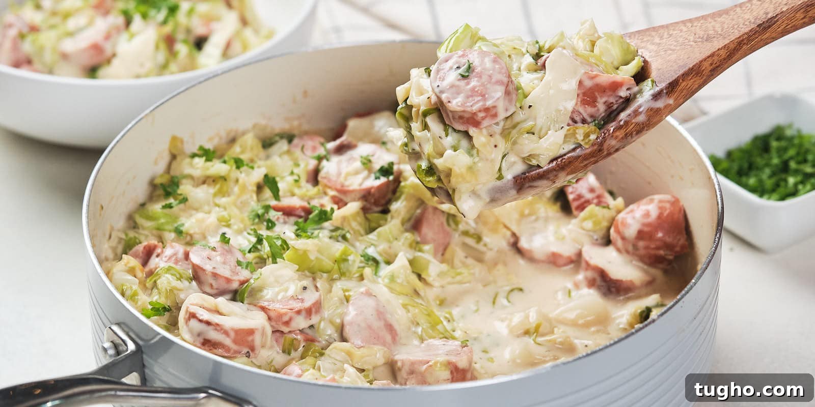 17 No-Fuss Dinners That Make the Whole Family Smile 17 A skillet containing a creamy cabbage and sausage alfredo garnished with herbs.