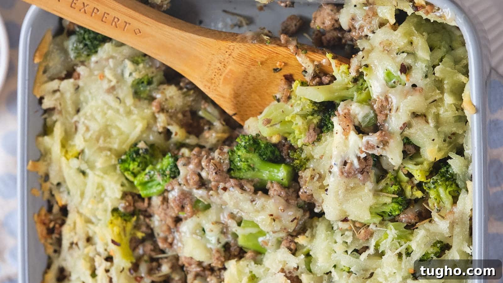17 No-Fuss Dinners That Make the Whole Family Smile 18 A baked casserole dish with ground beef and broccoli casserole and a wooden spoon.