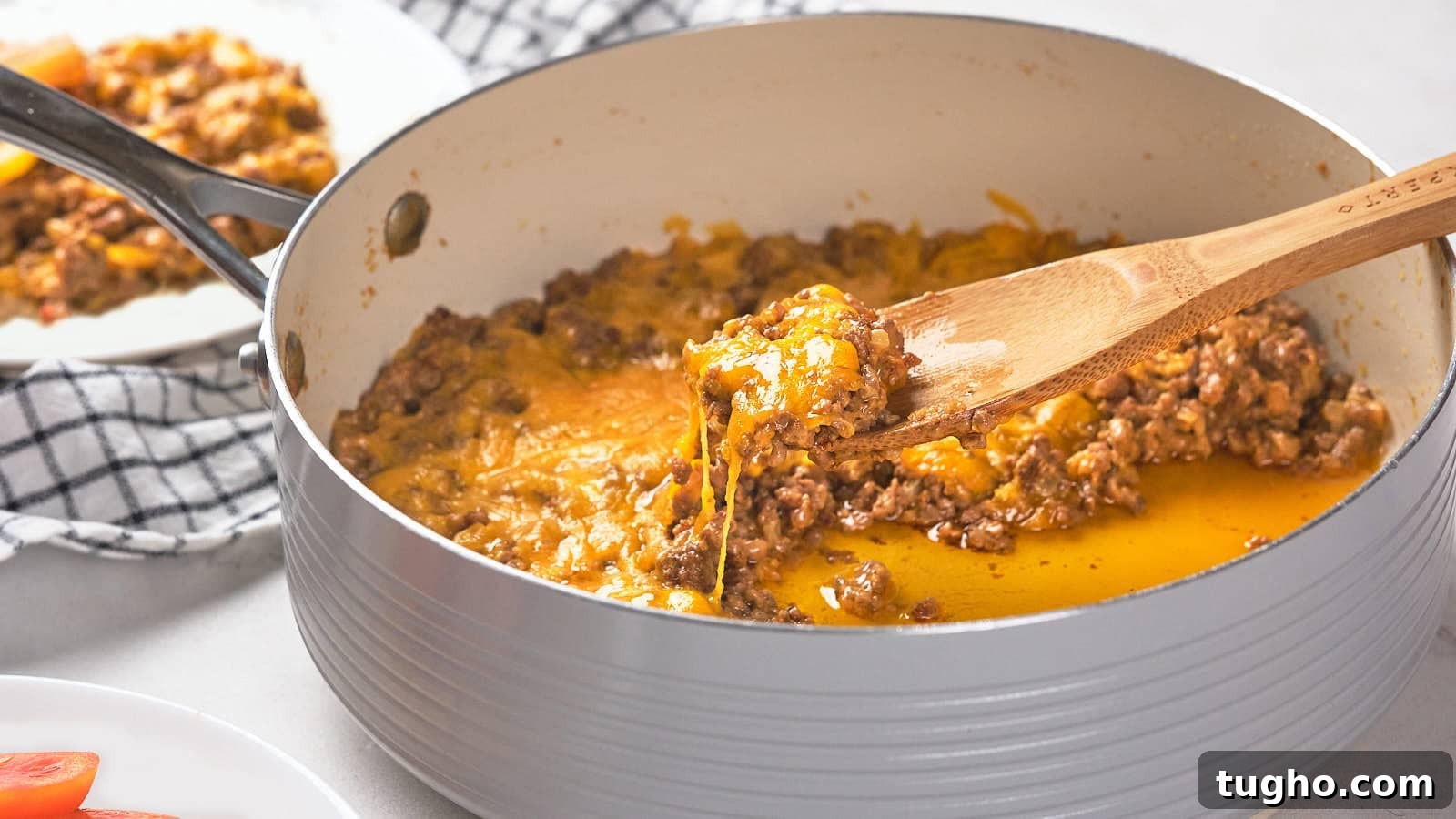 17 No-Fuss Dinners That Make the Whole Family Smile 5 A wooden spoon scoops a portion of cooked ground meat with melted cheese from a pan.