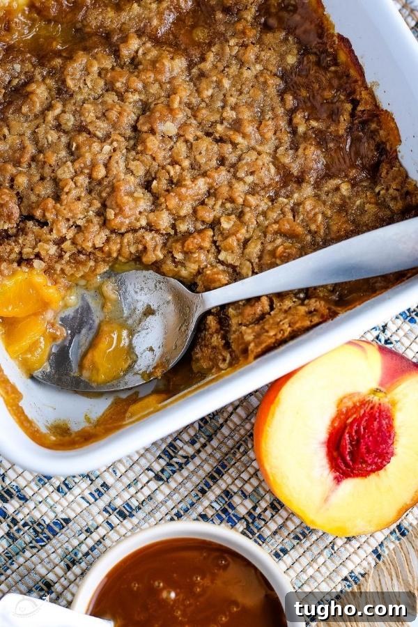Peach Oat Crumble Recipe 4 top view of peach crumble with an oat topping in a white casserole dish with a spoon
