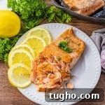 cast iron cooked salmon on a white plate with lemon slices
