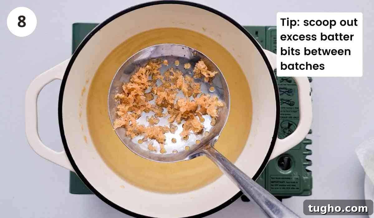 Homemade Crispy Honey Sesame Chicken Recipe 8 crispy batter on a slotted spoon with caption