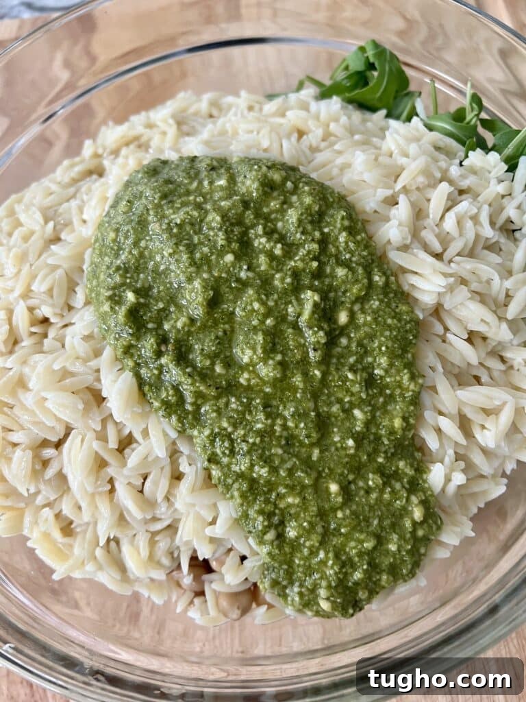 Pesto Orzo Caprese Salad with Cherry Tomatoes and Mozzarella 5 Basil pesto poured over cooked orzo about to be mixed in.