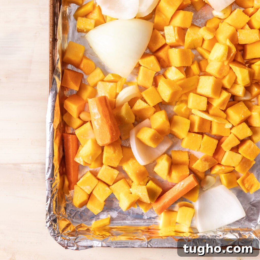 Velvety Roasted Butternut Squash and Carrot Soup Recipe 4 chopped butternut squash, carrot, onion, and garlic on a foil lined sheet pan