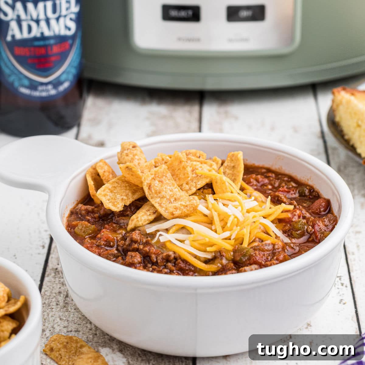 Close up side view of a bowl of beer chili with a crock pot in the background.