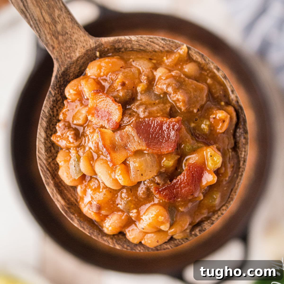 a close up of a spoon full of baked beans with bacon