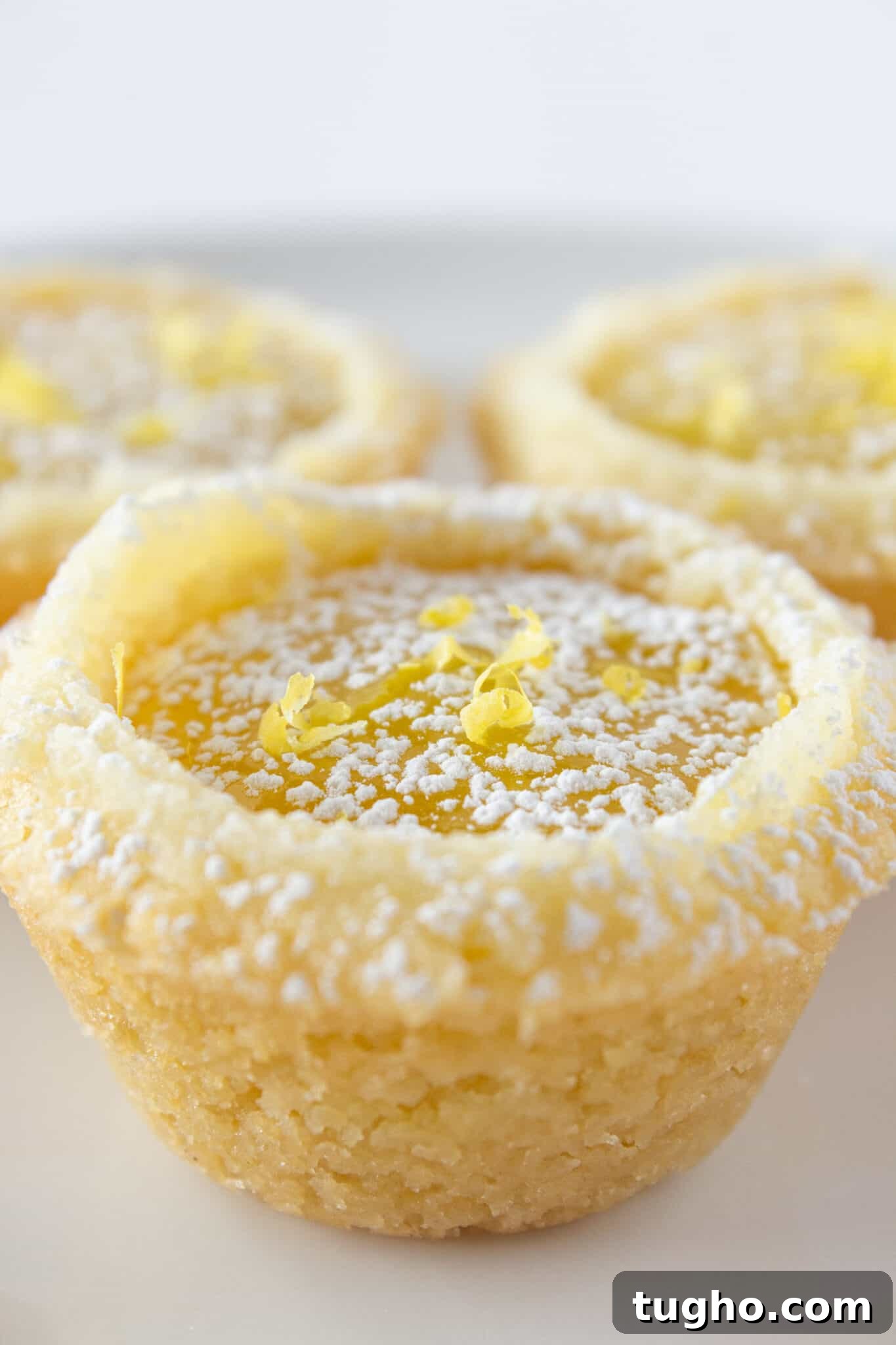 Lemon Bar Cookie Cups Recipe: Zesty Citrus Dessert Cups 2 3 Lemon Bar Cookie Cups on a white plate.
